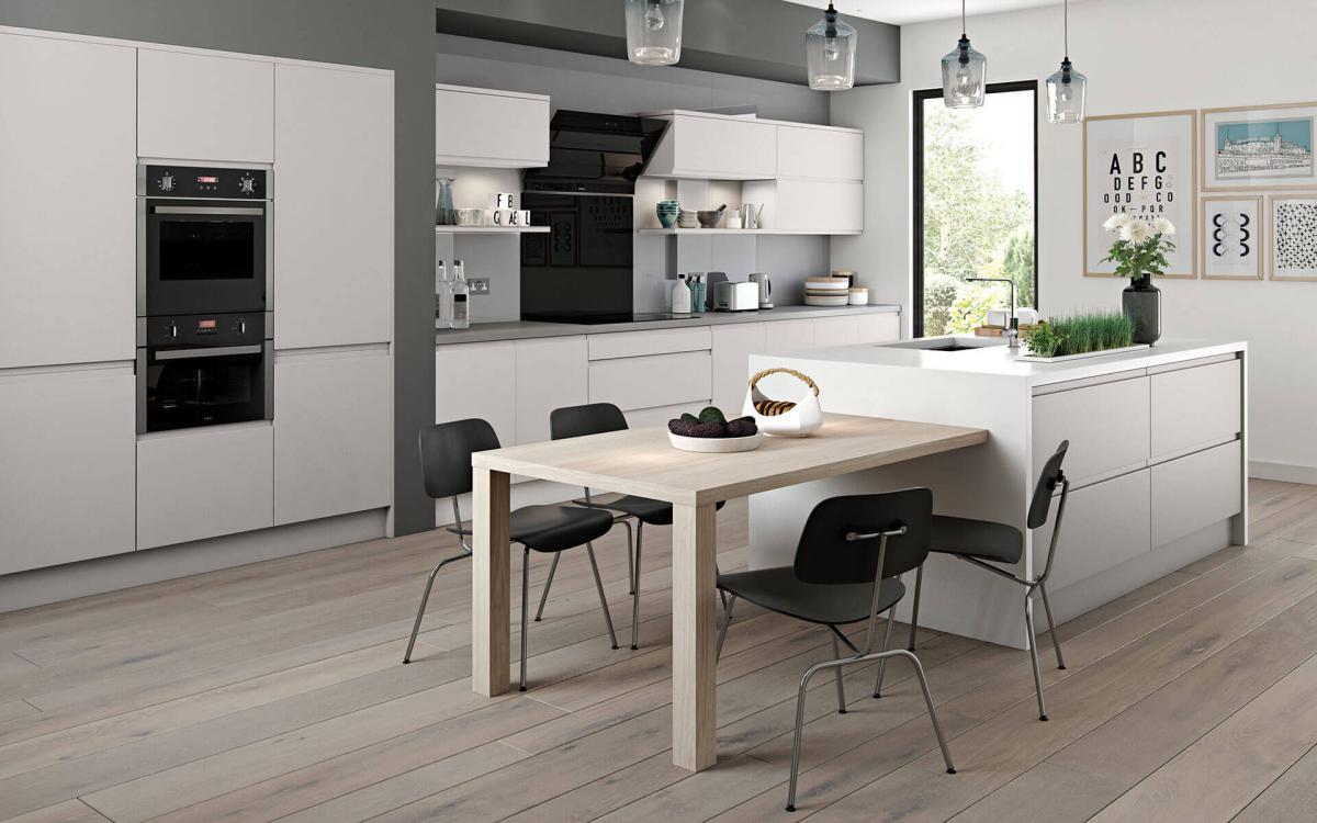 Spacious kitchen with white worktop island, waterfall end features, and recessed bank of tall units in Marino Pebble style