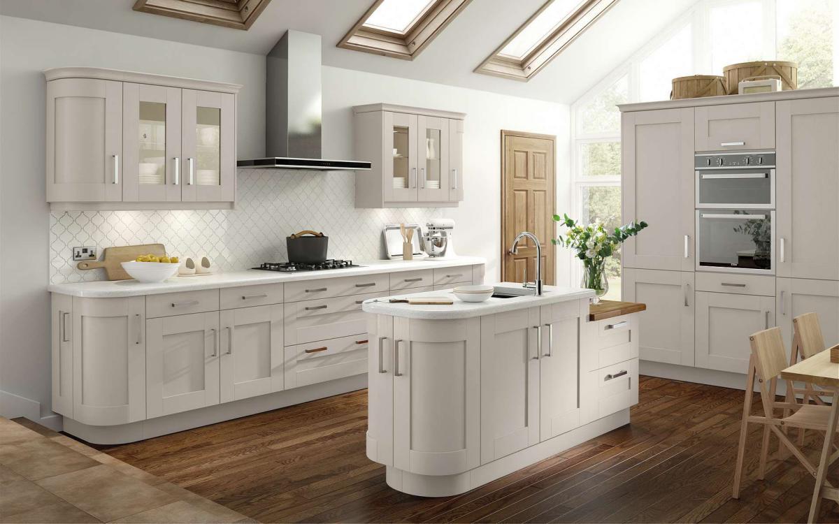 Kitchen with radius end to the island, glass wall units, and three tall units housing a double oven in Bowood Taupe style