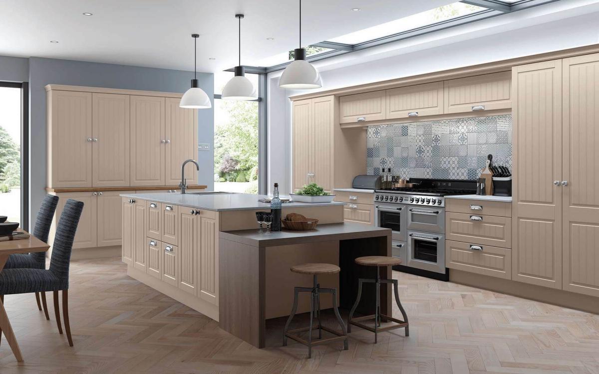 Open kitchen with large island, low walnut tabletop, large feature dresser, and geometric tiles in Tamar Stone Grey style