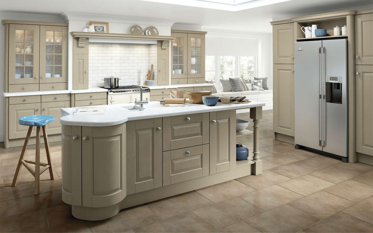 Open plan country kitchen with built-in American fridge, curved island feature, and glass door dresser units in Fleetwood Stone Grey style