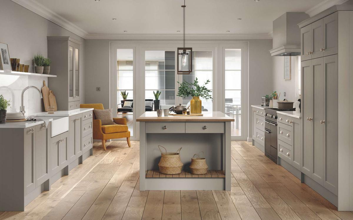 Kitchen with island in the middle, two galleys, Belfast sink area, and range cooker with feature canopy in Seaton Taupe style